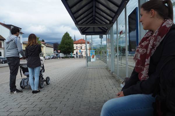 Junges Paar mit Kinderwagen an Bushaltestelle